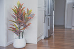 Colourful artificial indoor plant styled in a large white pot